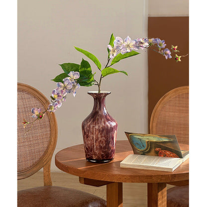 Decorative glass vase with purple flowers in reading corner
