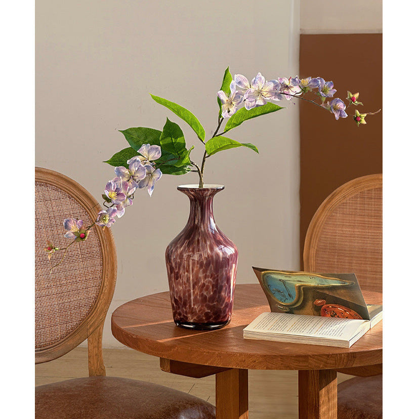 Decorative glass vase with purple flowers in reading corner