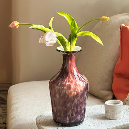 Purple glass flower vase with yellow tulips on sofa table