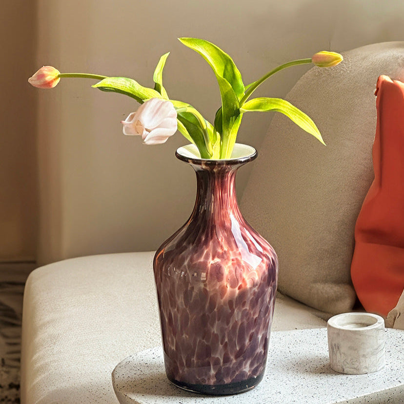 Purple glass flower vase with yellow tulips on sofa table